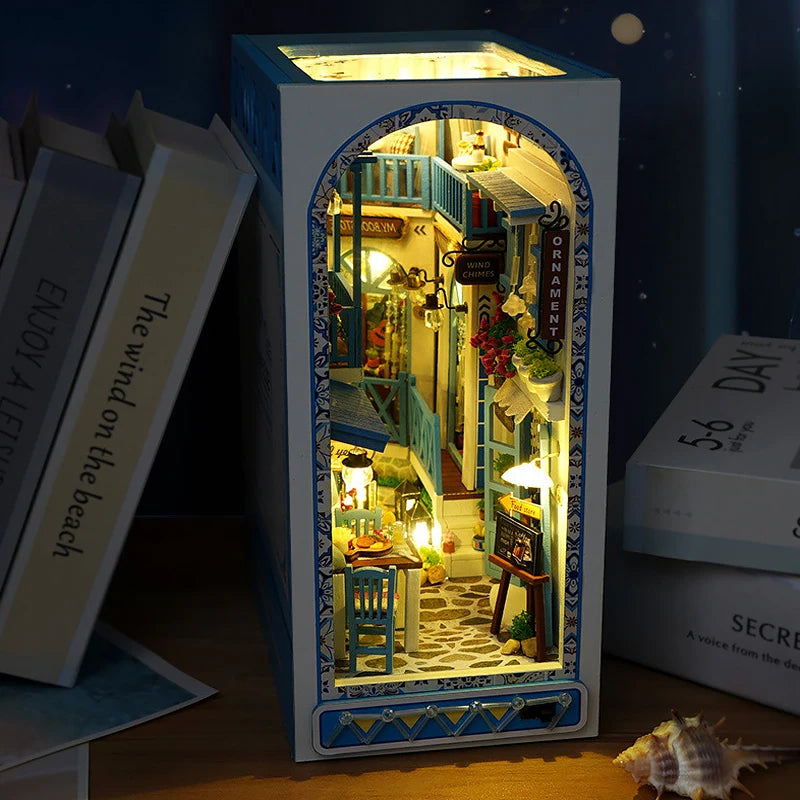 A DIY book nook kit featuring a wooden bookshelf insert with warm LED lighting and decorative elements.