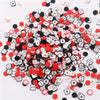 A pile of small polymer clay flower charms in black and white with red accents for DIY crafts.