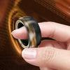 A hand is holding a black and gold magnetic fidget ring, showing its texture and design.