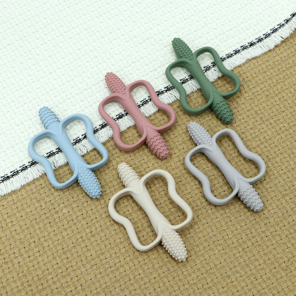 A collection of silicone teething sticks in various pastel colors, including pink, mint green, and light blue, resting on a b