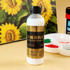 A clear bottle of 100ml acrylic painting medium with a black cap sits in front of a yellow sunflower background.
