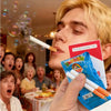 A hand holds a blue novelty cigarette bubble blower with white cigarettes, set against a background of people.