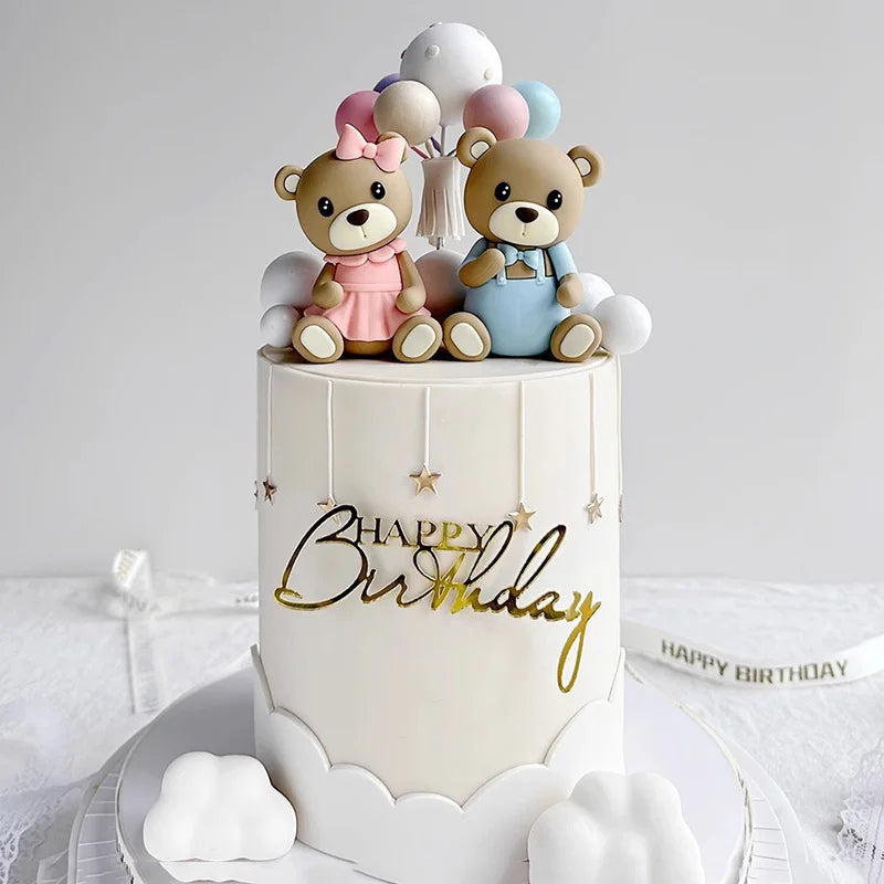 A white birthday cake decorated with three adorable bear figures and gold lettering on the side.