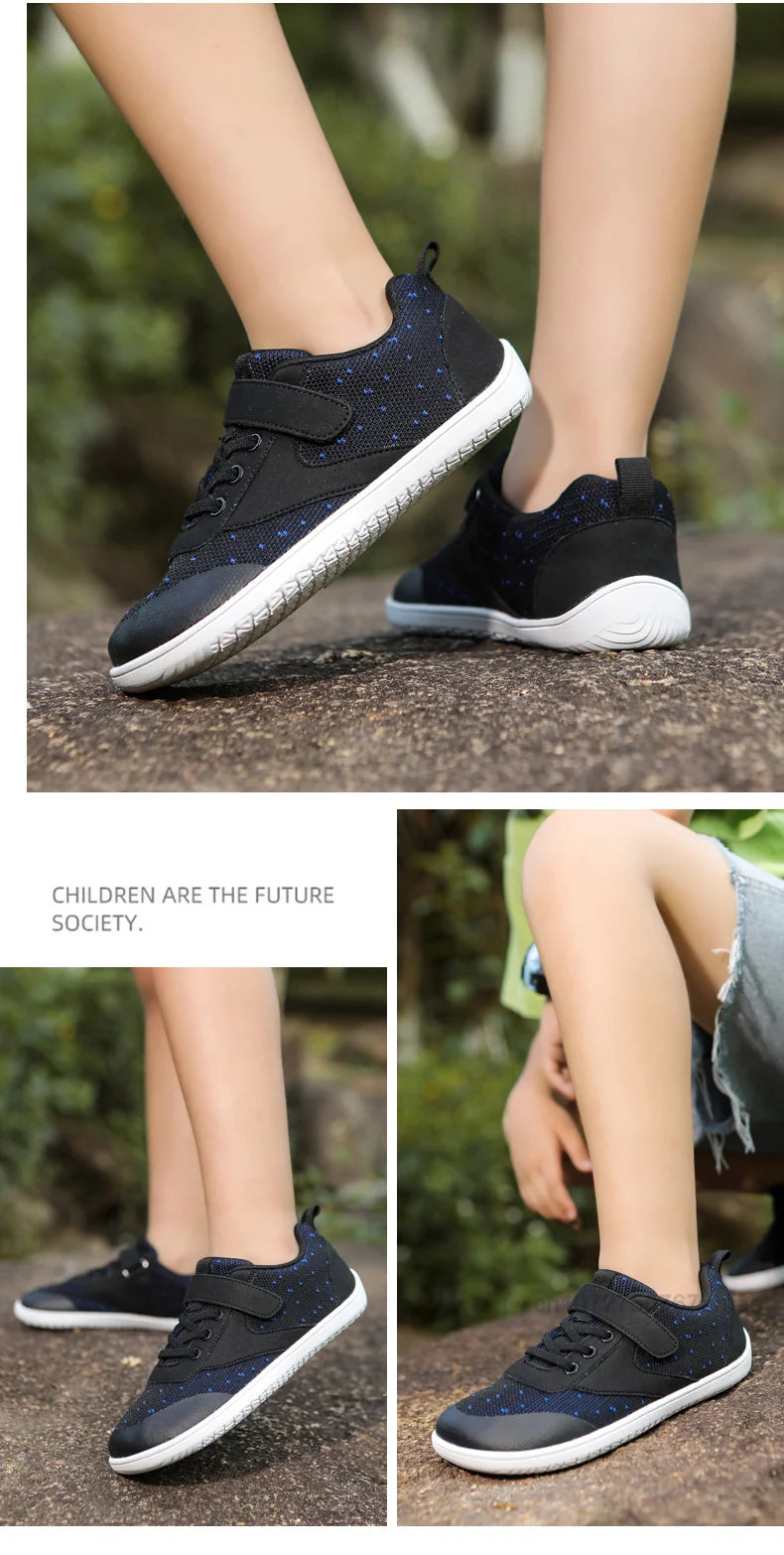 A pair of navy blue and white kids barefoot training sneakers worn by a child on a stone surface.