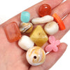 A hand holds a collection of colorful, translucent acrylic beads in various shapes and colors for jewelry making.
