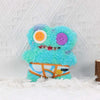 A fluffy, bright blue and purple monster plush toy with large eyes and an orange belly, displayed against a white textured ba