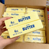 A hand holds several yellow butter squishy toys packaged in a box.
