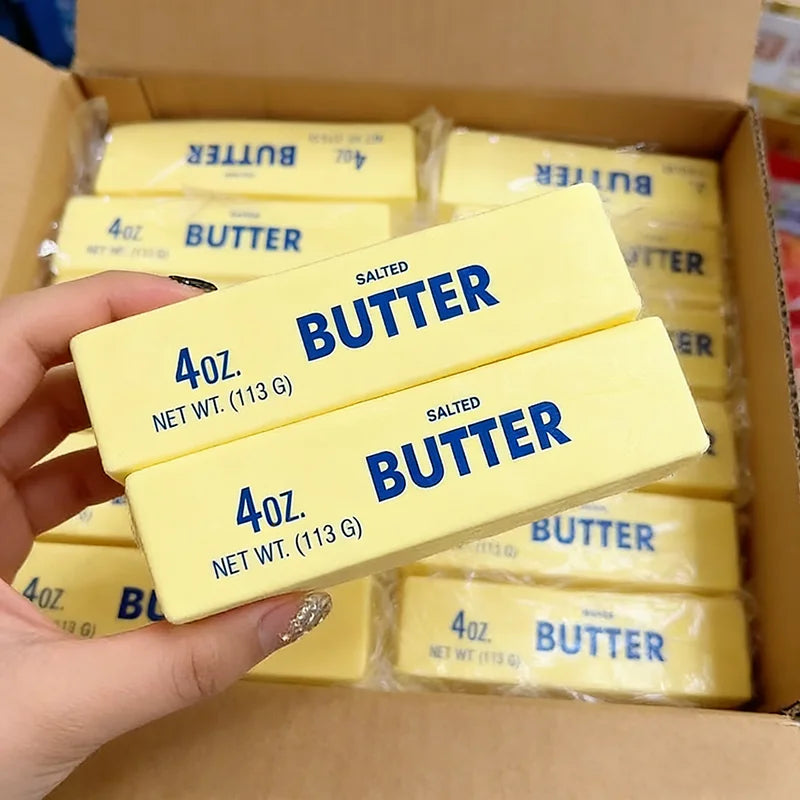 A hand holds several yellow butter squishy toys packaged in a box.