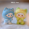 A pair of cute, fuzzy cat figurines in blue and yellow are displayed together on a white surface.