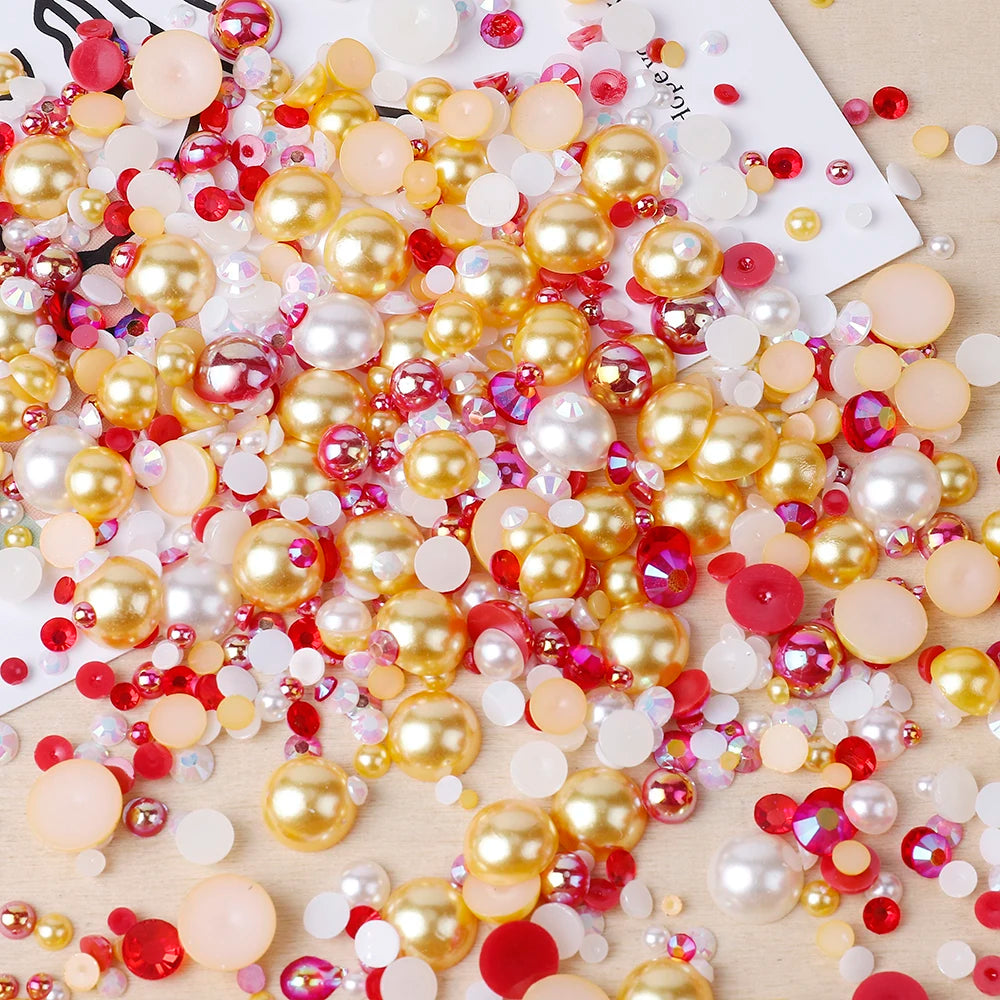 A scattered collection of mixed resin and glass pearls in various shades of pink, gold, and red for craft and nail art.
