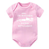 Pink knitted baby romper featuring text that says I'm watching racing with daddy