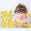 A baby is looking down at a set of yellow rubber ducks floating in water.