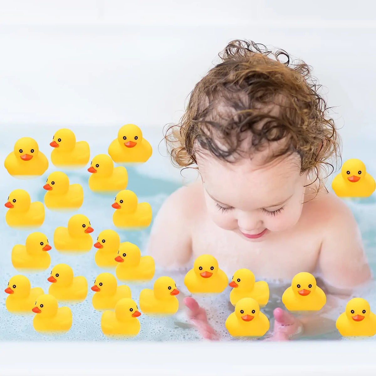 A baby is looking down at a set of yellow rubber ducks floating in water.