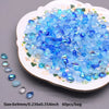 A pile of clear blue and blue-green water drop glass beads for jewelry making displayed on a white plate.