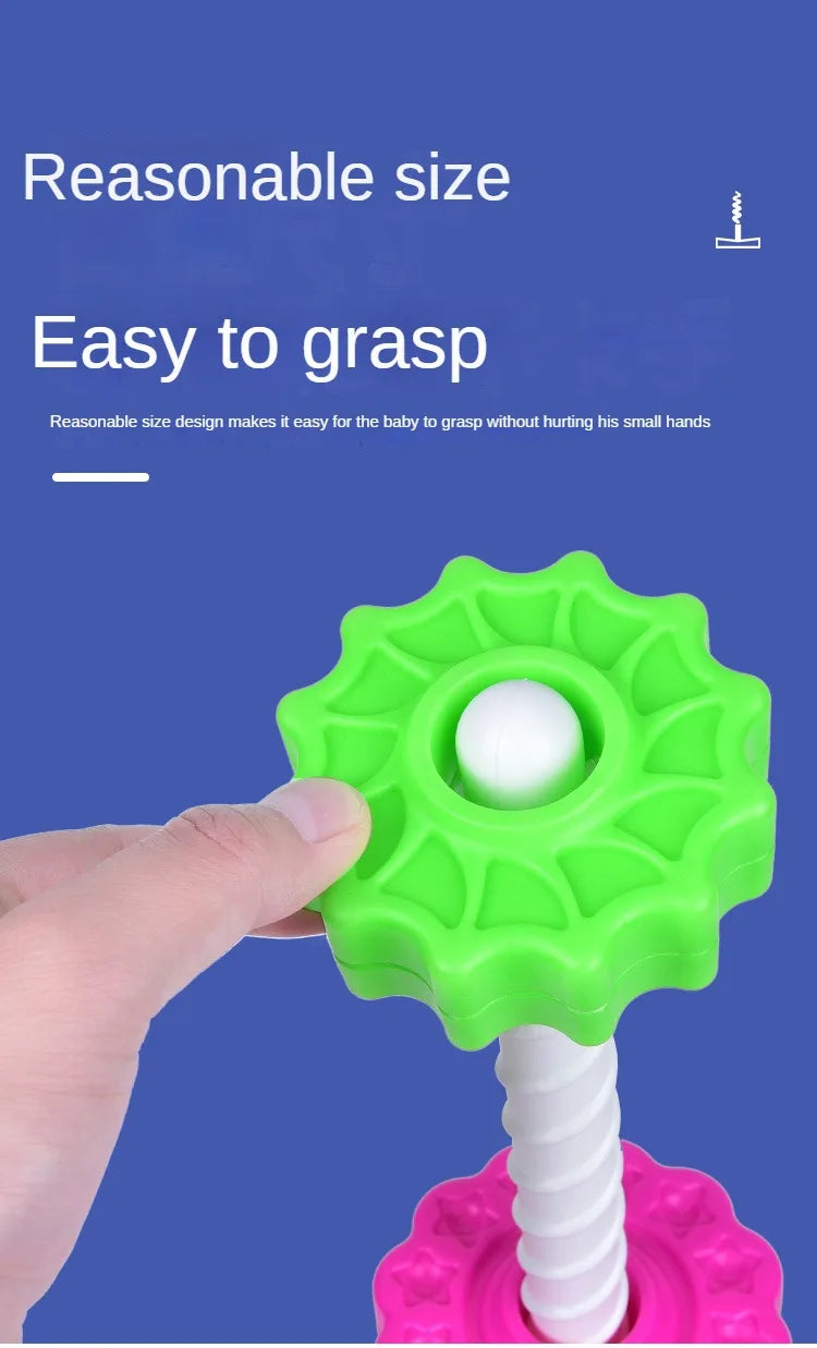 A hand is grasping a bright green spin tower toy with a white ball on top, demonstrating its easy to grasp design.