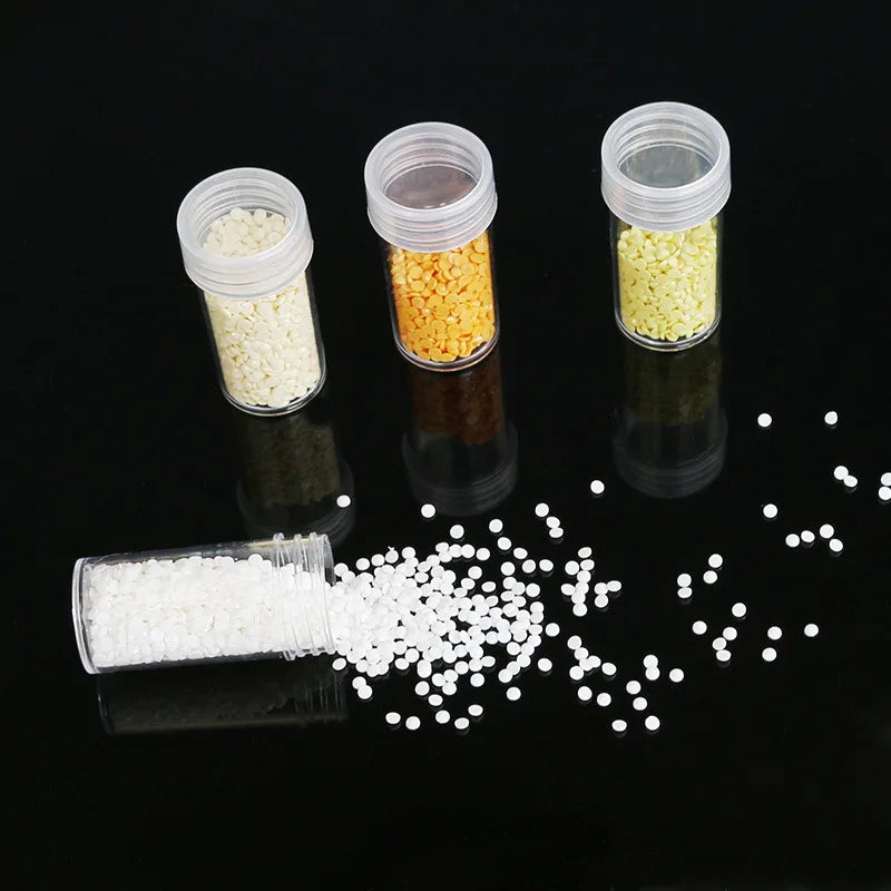 Three clear plastic storage bottles filled with different colored beads for diamond painting and crafts