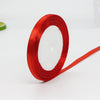 A roll of bright red satin ribbon used for gift wrapping or crafts.