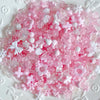 A pile of pink and white acrylic bow and flower beads for DIY jewelry making