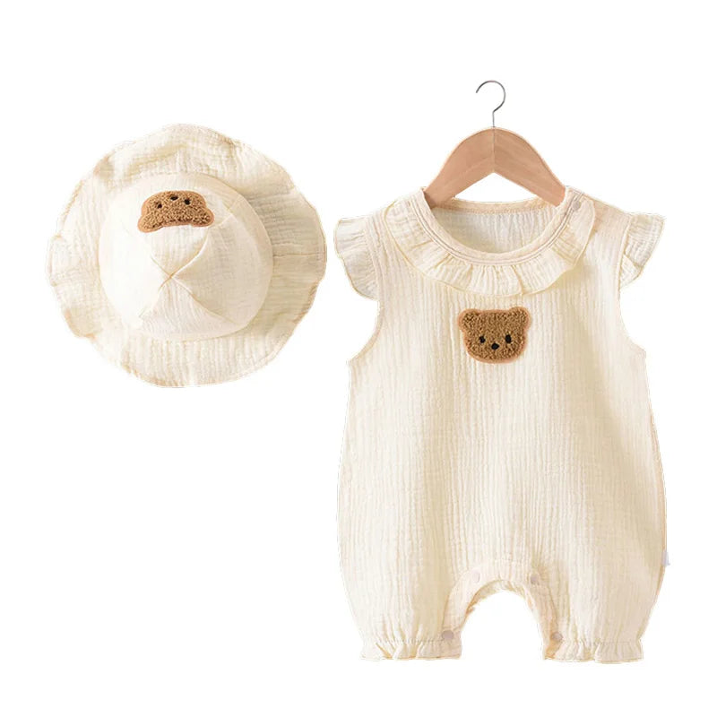 A cream cotton muslin baby romper and hat set featuring a bear appliqué.