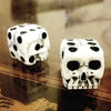 A set of mini white skull dice used for Halloween and party games resting on a dark surface.