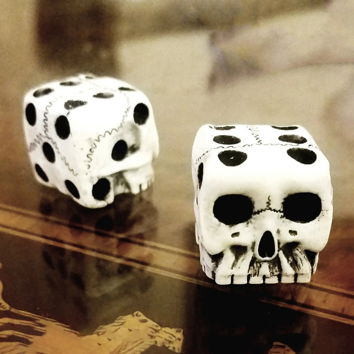 A set of mini white skull dice used for Halloween and party games resting on a dark surface.