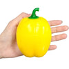 A hand is holding a bright yellow bell pepper with a green stem.