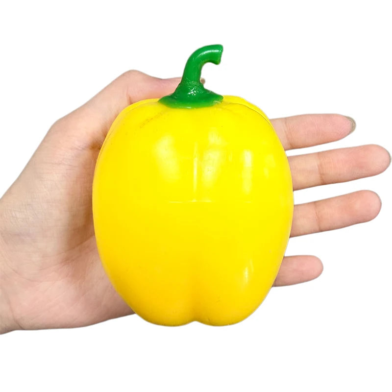 A hand is holding a bright yellow bell pepper with a green stem.