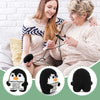 Two women smiling while holding a handmade crochet penguin doll with a positive message card