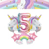 A pink foil number five balloon shaped like a unicorn and a rainbow arch decoration for a girl's birthday party