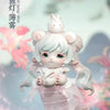 A white collectible figurine of a cute, round-faced creature with pink accents and flowing hair, set against a soft, light ba