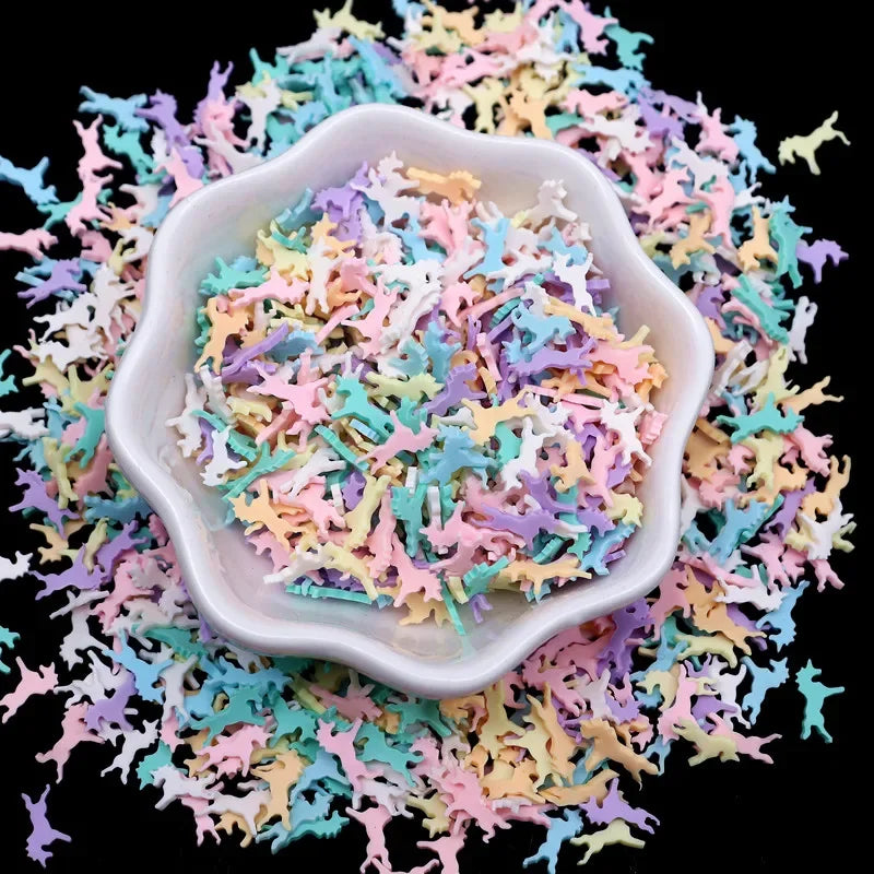 A white dish filled with colorful polymer clay sprinkles mixed with small plastic figures, scattered on a black background.