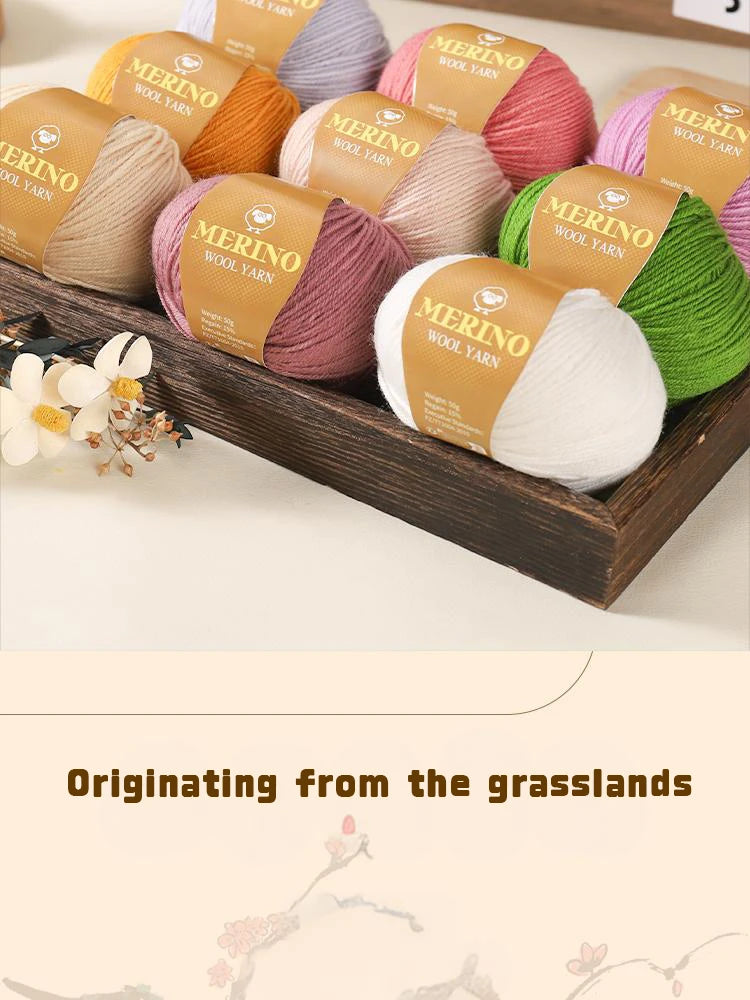 A collection of Merino wool yarn in various shades of pink, yellow, green, and beige is displayed in a wooden box.