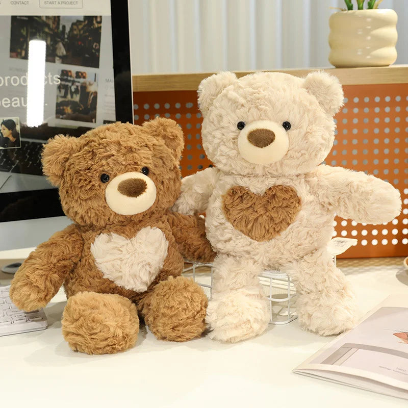 A light beige teddy bear plush toy sitting on a white surface next to a glossy display stand.