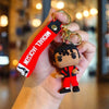 A hand holds a keychain featuring a figurine of Michael Jackson in a red suit and black skin, attached to a metal buckle.