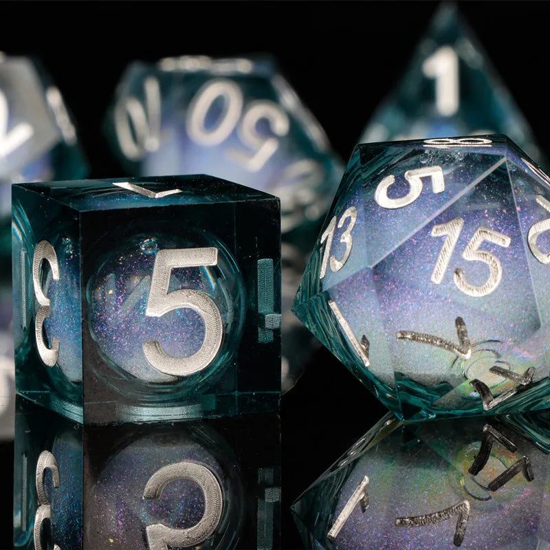 A close-up of a set of translucent blue and purple liquid core dice, including a d6 and d10 shapes.