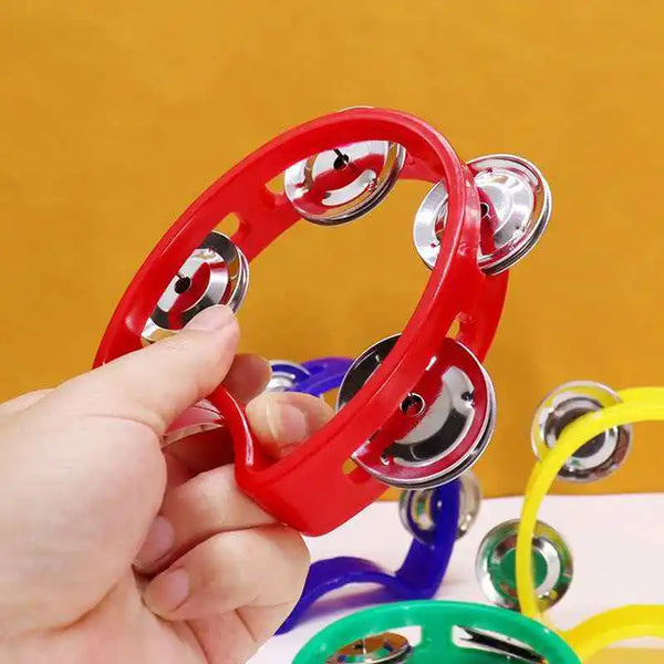 A hand holds a red handheld percussion tambourine with silver jingles against a yellow background.