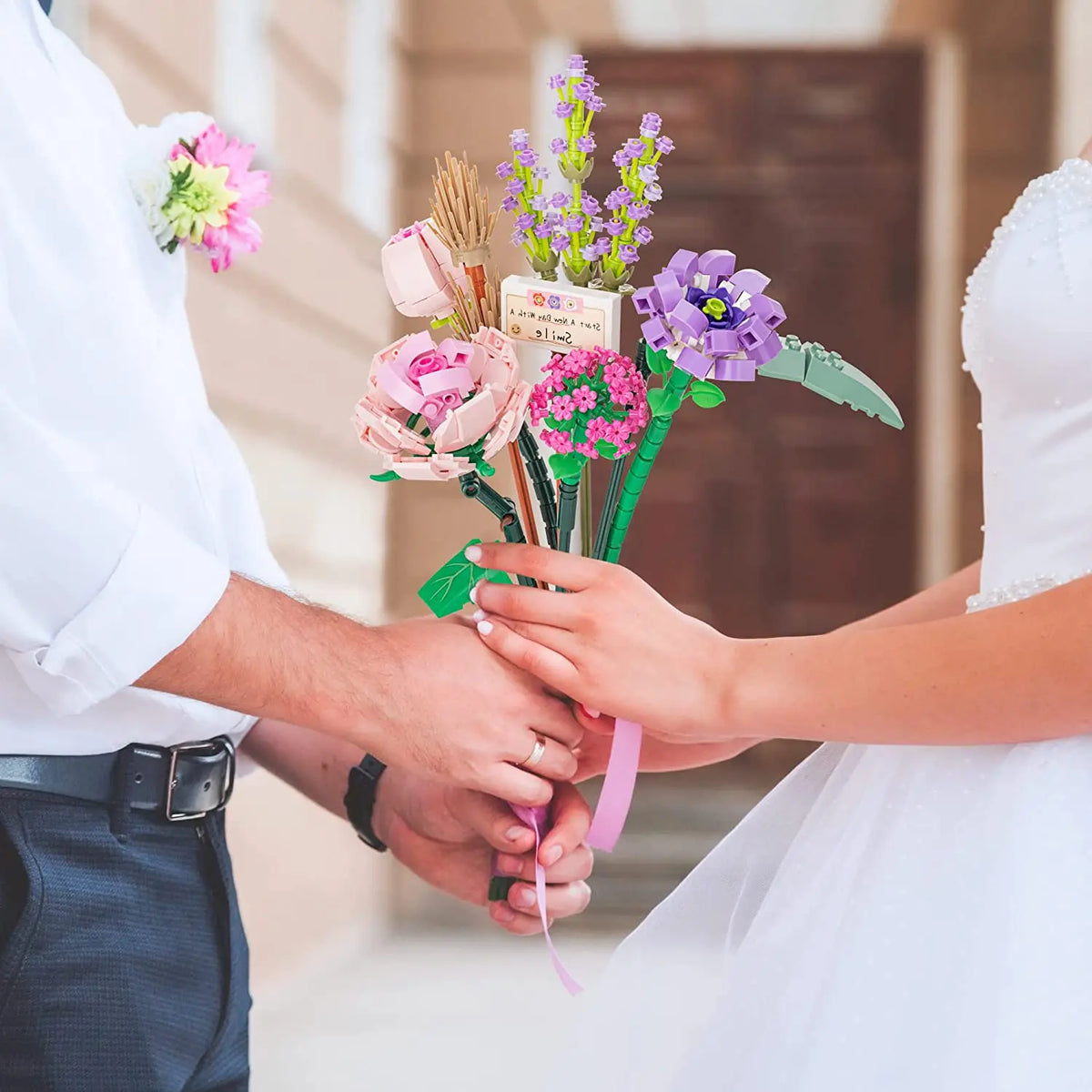 A bride and groom are holding a colorful floral bouquet made from building blocks for a wedding display.