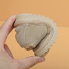 A hand holds a tan cozy leather winter boot for toddlers with an anti-slip rubber sole.