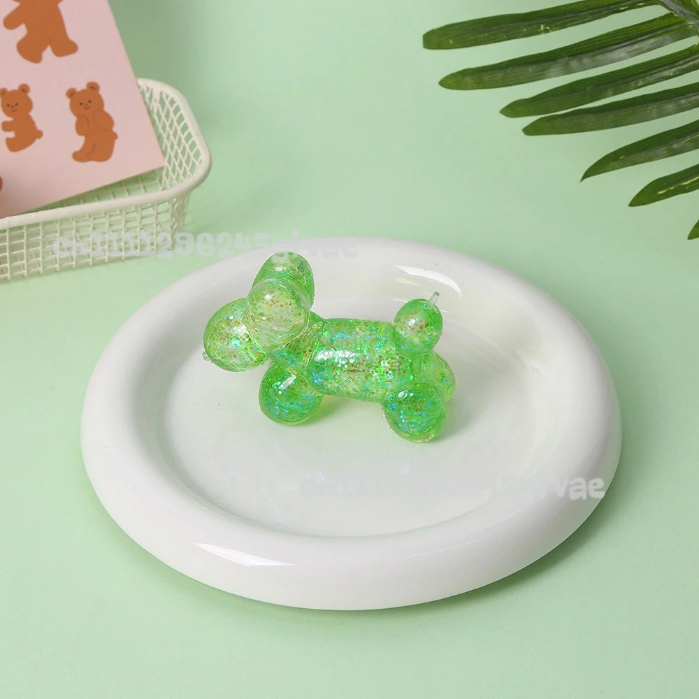 A translucent green squishy toy shaped like a bear sitting on a white plate with a pink background nearby.