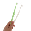 A hand holds a pair of orthodontic interdental brushes, one green and one white.