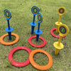 A set of classic ring toss game featuring five colored rings and corresponding stakes on green grass.