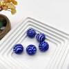 Collection de billes en verre marbrées bleu et blanc disposées sur un plateau blanc.