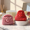 A set of silicone molds in pink and red for making candles and soaps displayed on a marble surface.