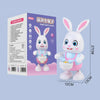 A white rabbit-shaped musical robot toy with pink accents and LED lights, standing on a display card.