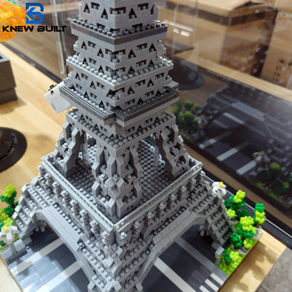 A detailed miniature model of the Eiffel Tower built from gray LEGO-style blocks on a black and white grid surface.