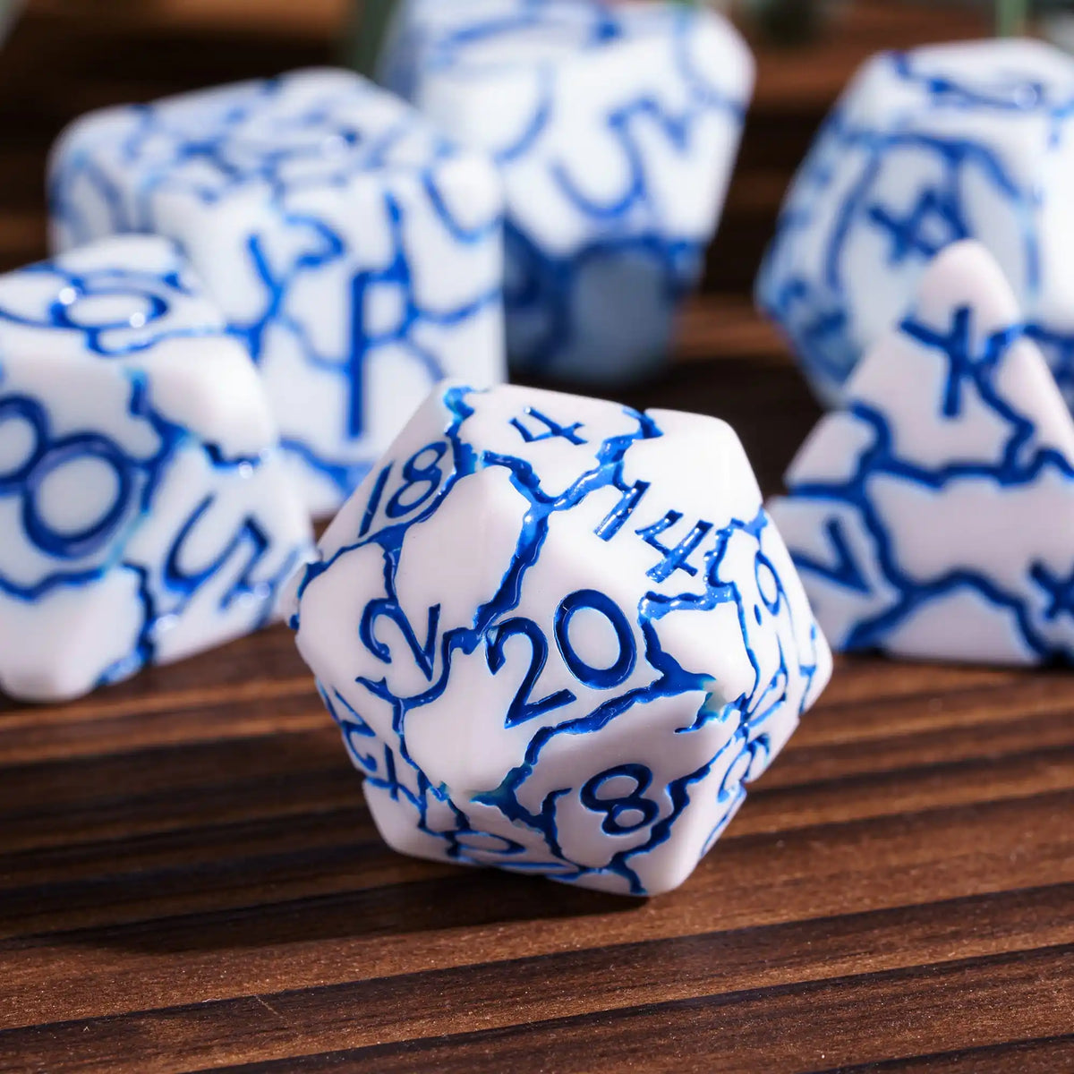 A close-up of several white dice with blue markings are scattered on a wooden surface.