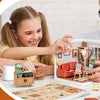 Two children are assembling a DIY miniature house kit for a neighborhood project.