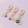 A set of three gold-toned evil eye keychains featuring blue and black irises