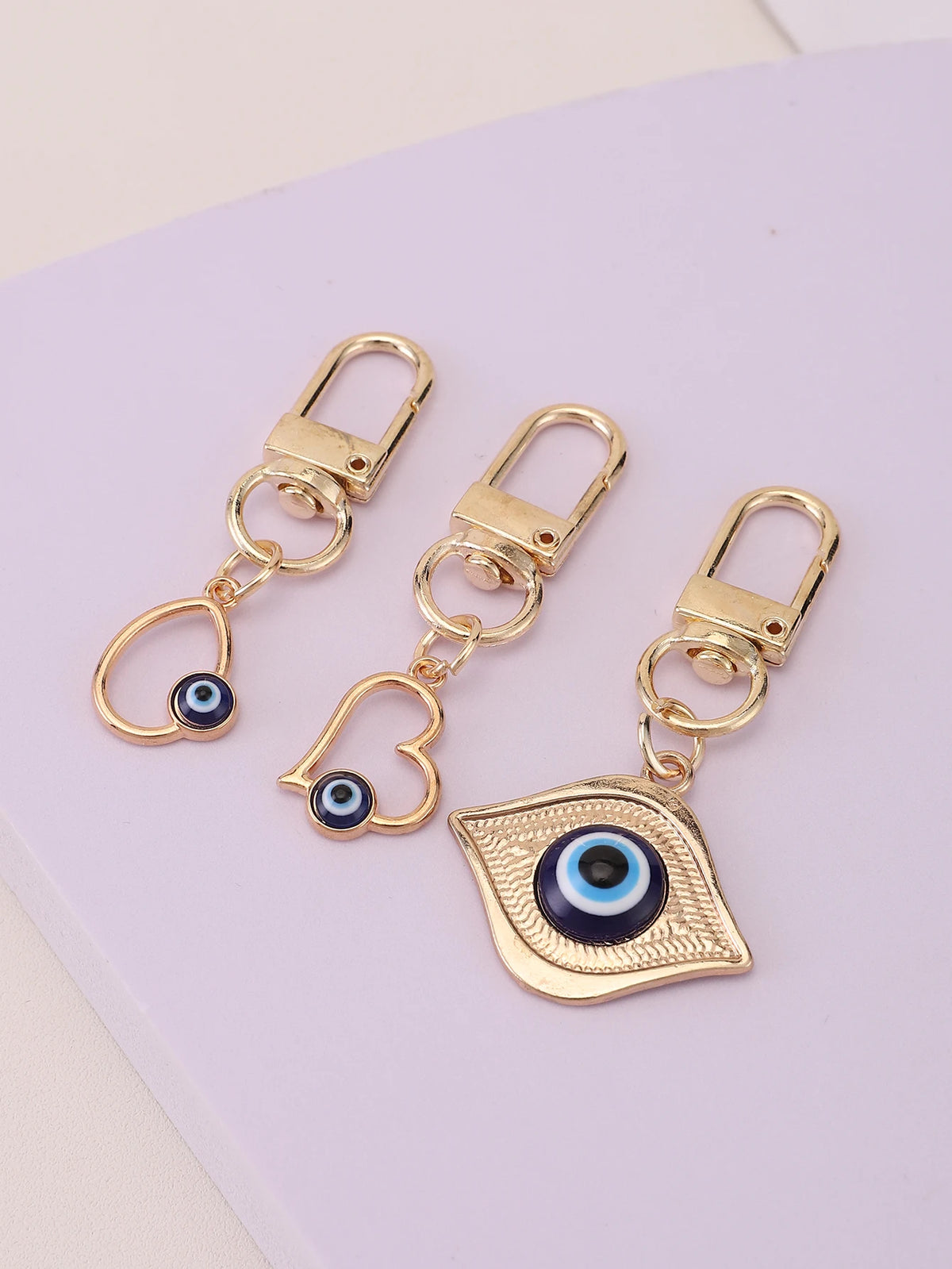 A set of three gold-toned evil eye keychains featuring blue and black irises