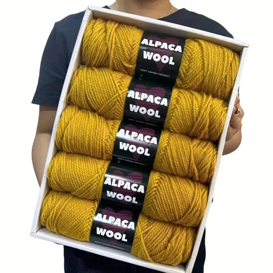 A box containing five skeins of yellow alpaca wool yarn for knitting and crochet.